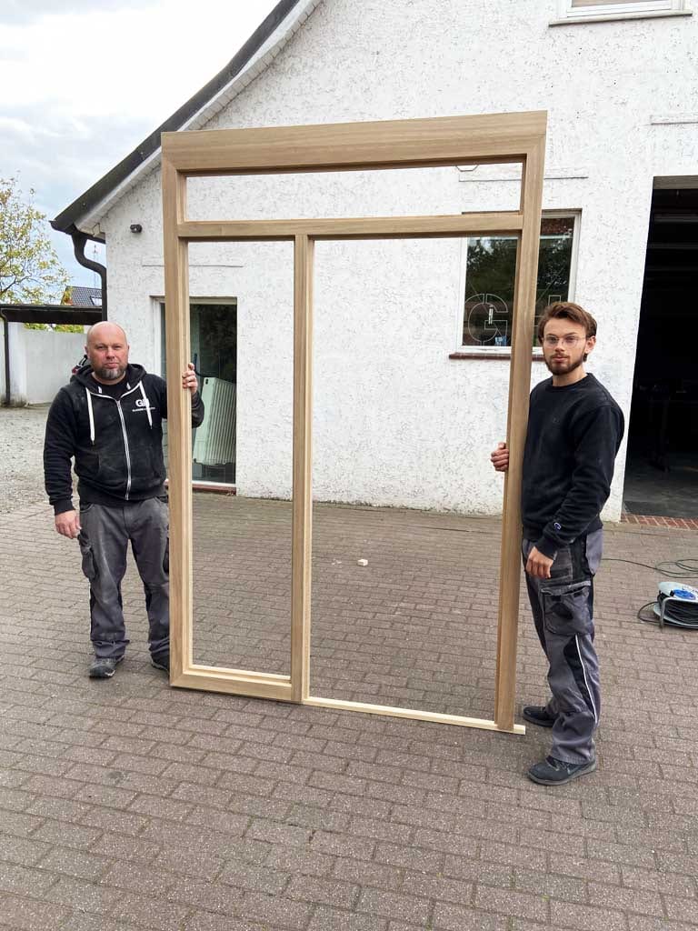 Alexander Honstein und sein Sohn vor der Werkstatt in Sudweyhe, zwischen sich ein fertiger Rahmen mit Oberlicht