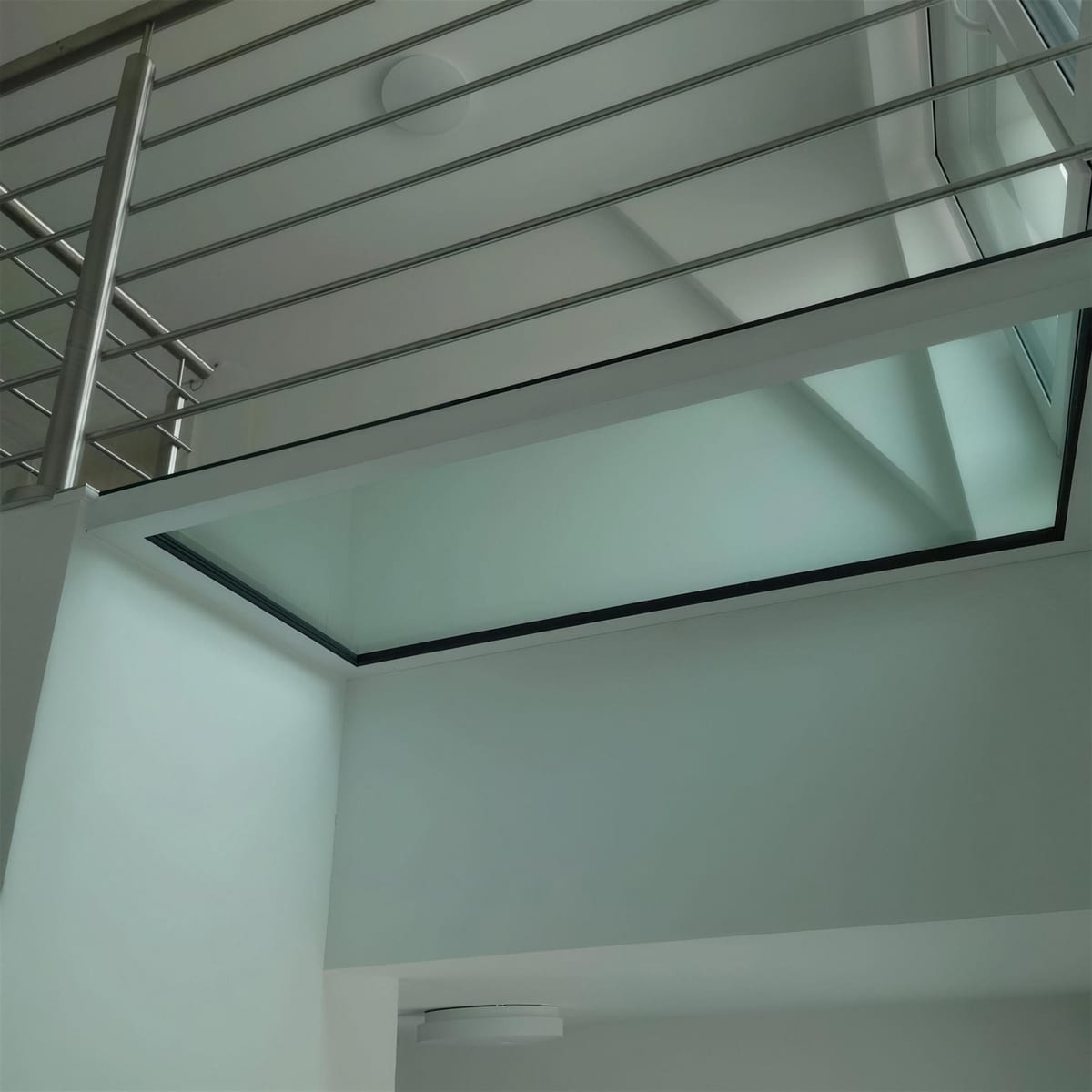 Blick von unten auf ein begehbares Glaselement in der Decke über dem Treppenlauf
