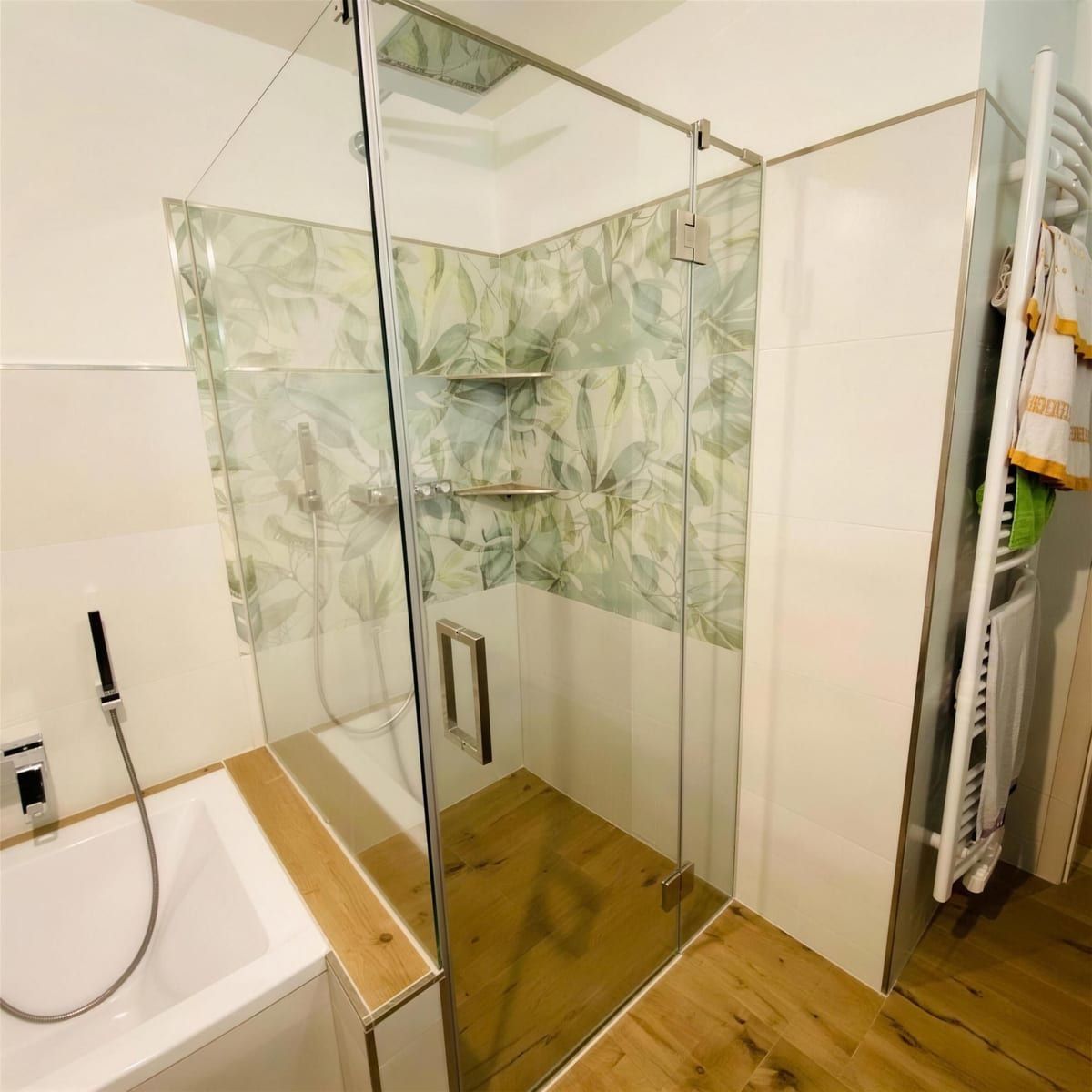 Über Eck geführte Duschabtrennung aus Glas neben einer Badewanne, gemusterte Wandfliesen
