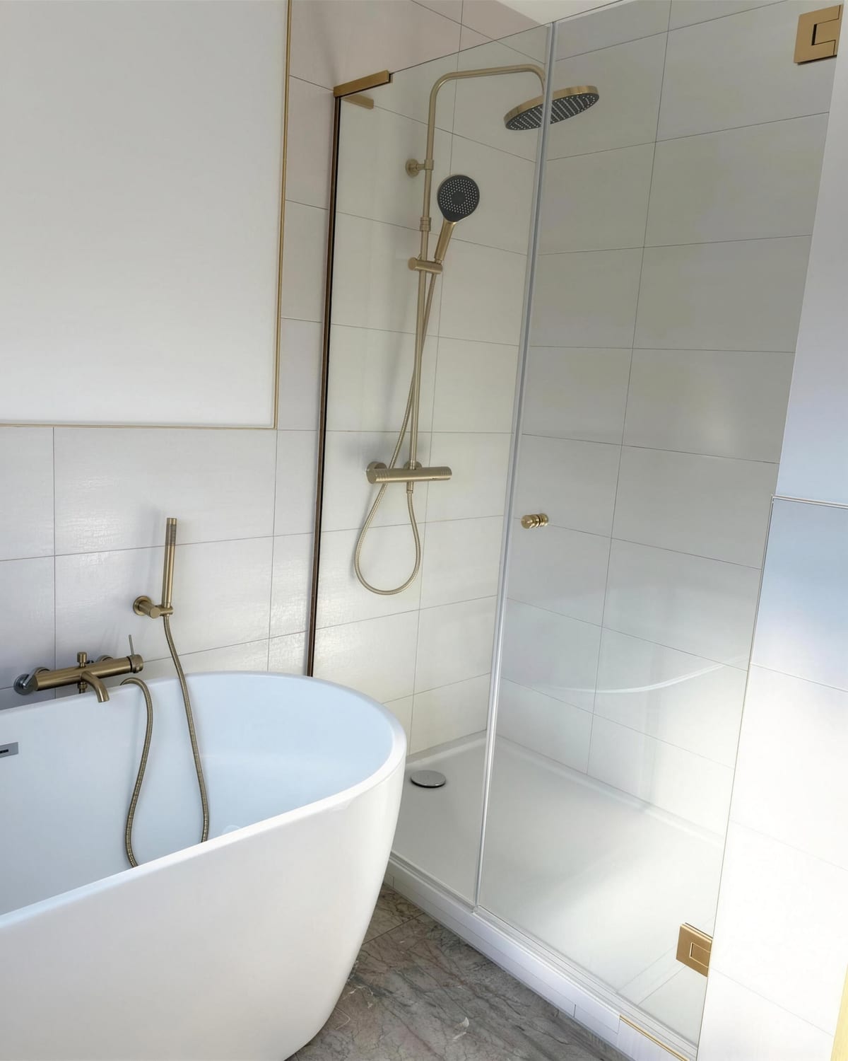 Feste Glasabtrennung neben einer freistehenden Badewanne, Armaturen in Messing