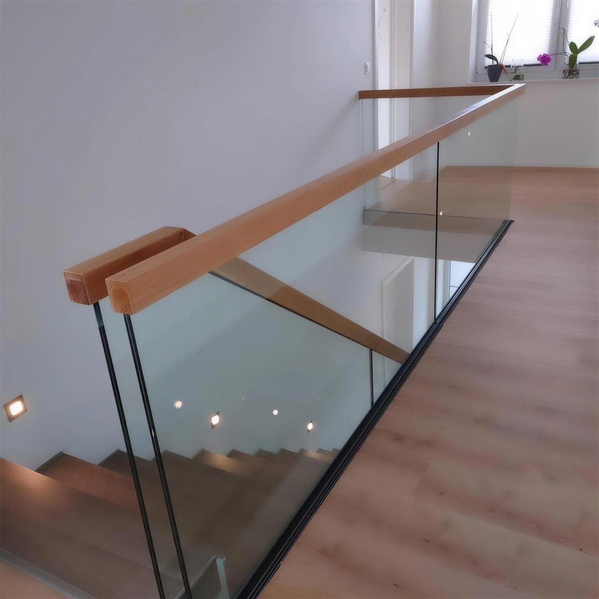 Glasbrüstung an einer Galerie mit Holzhandlauf, Blick in den Wohnraum darunter