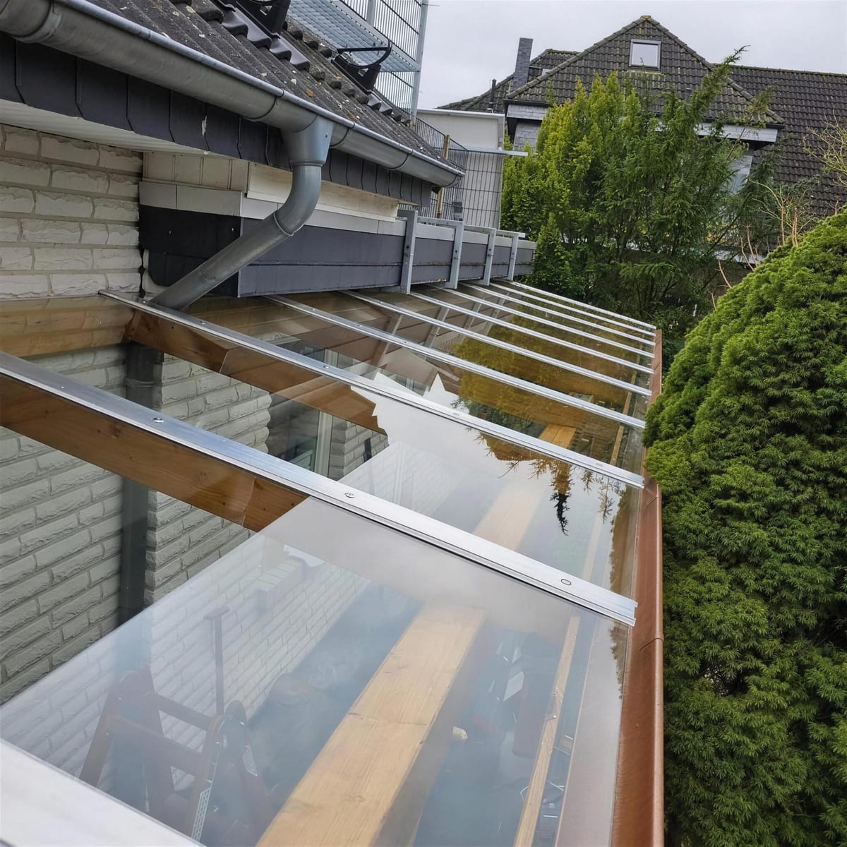 Glasüberdachung auf einer Holzunterkonstruktion an einer Klinkerfassade